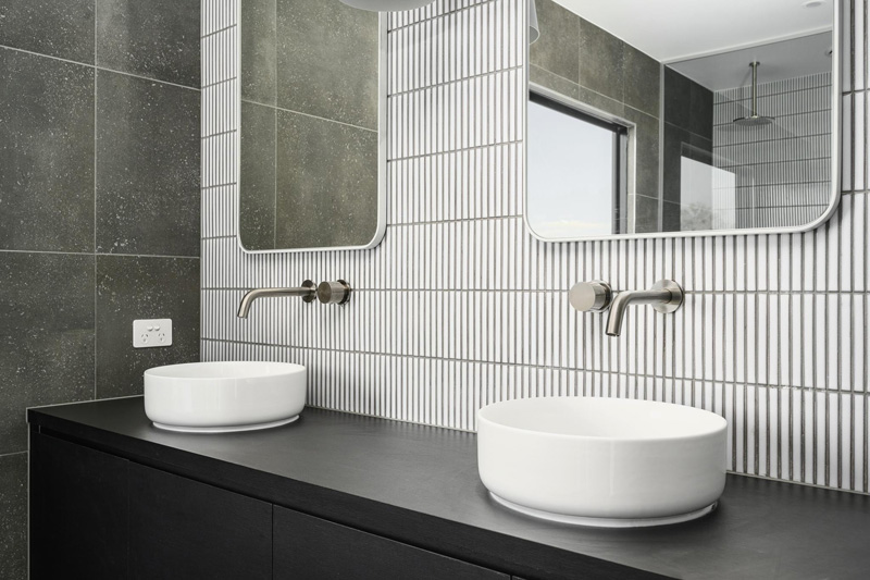 Close-up of two vessel basins against white finger tiles and grey tiles
