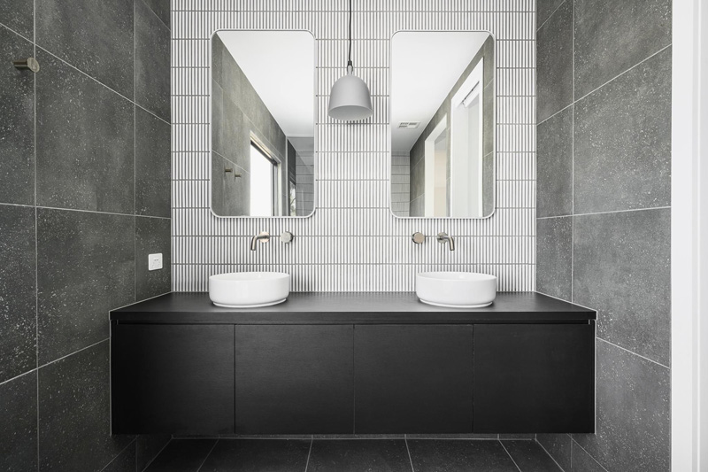 Double vanity with two mirrors, white finger tiles and dark grey wall tiles