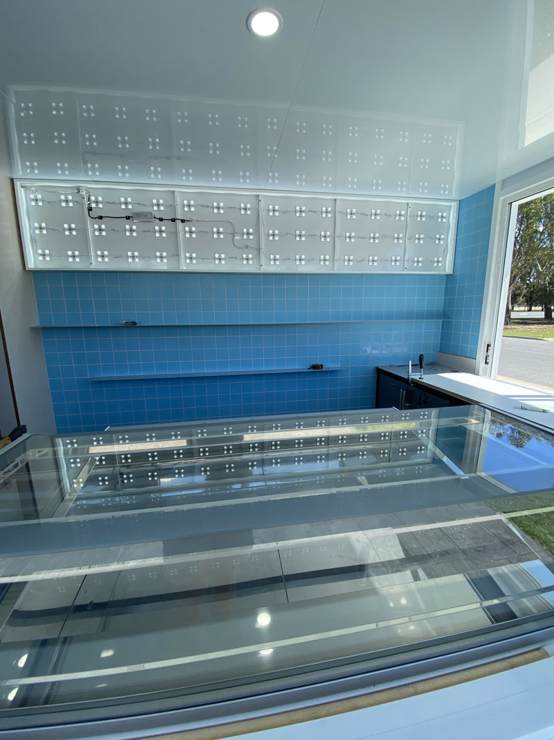 Blue wall tiles behind a glass display counter, seen from inside the shop