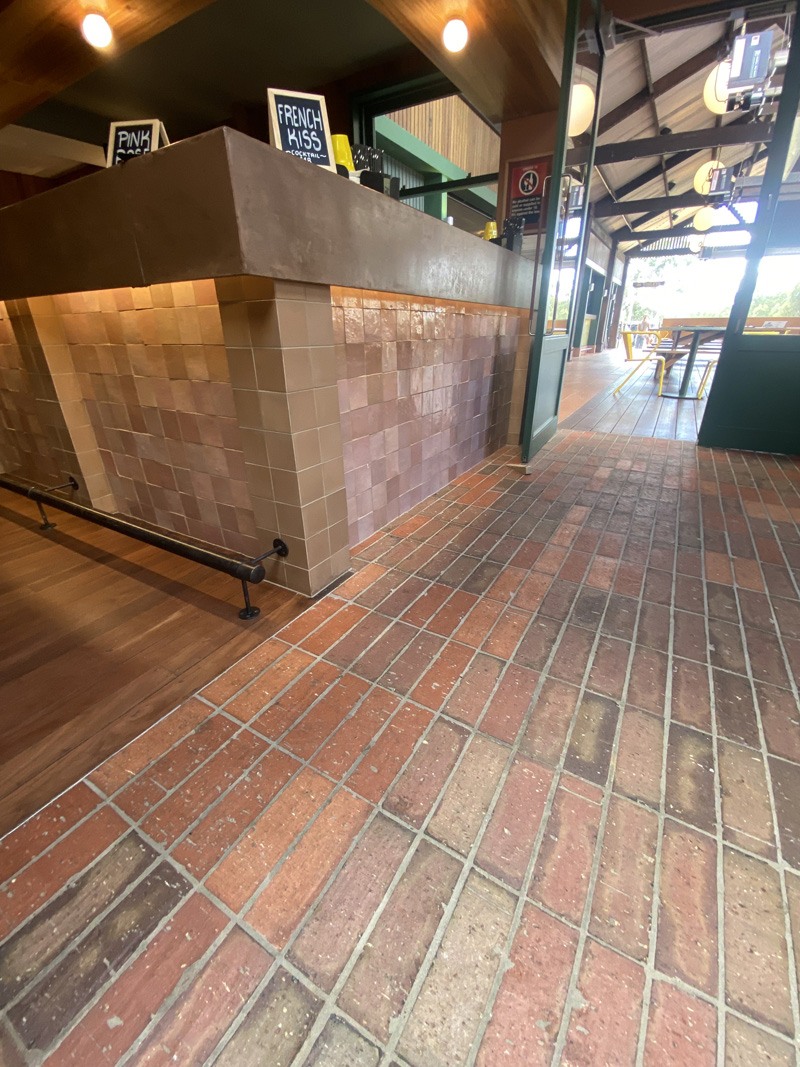 Brick-look floor tiles and pink wall tiles along a bar counter