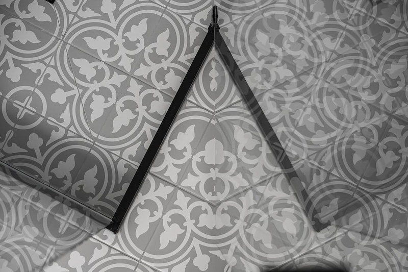 Black-and-white photo of patterned floor tiles with a V-shaped metal trim