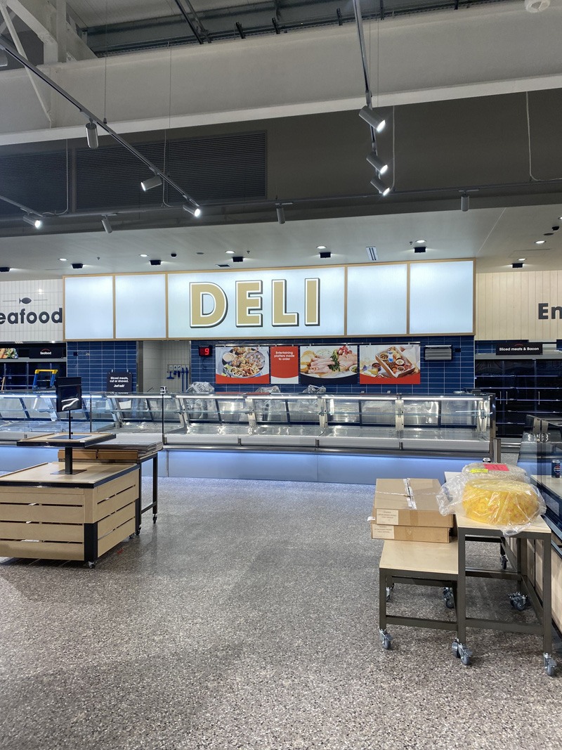 Supermarket deli section with blue wall tiles and speckled floor tiles