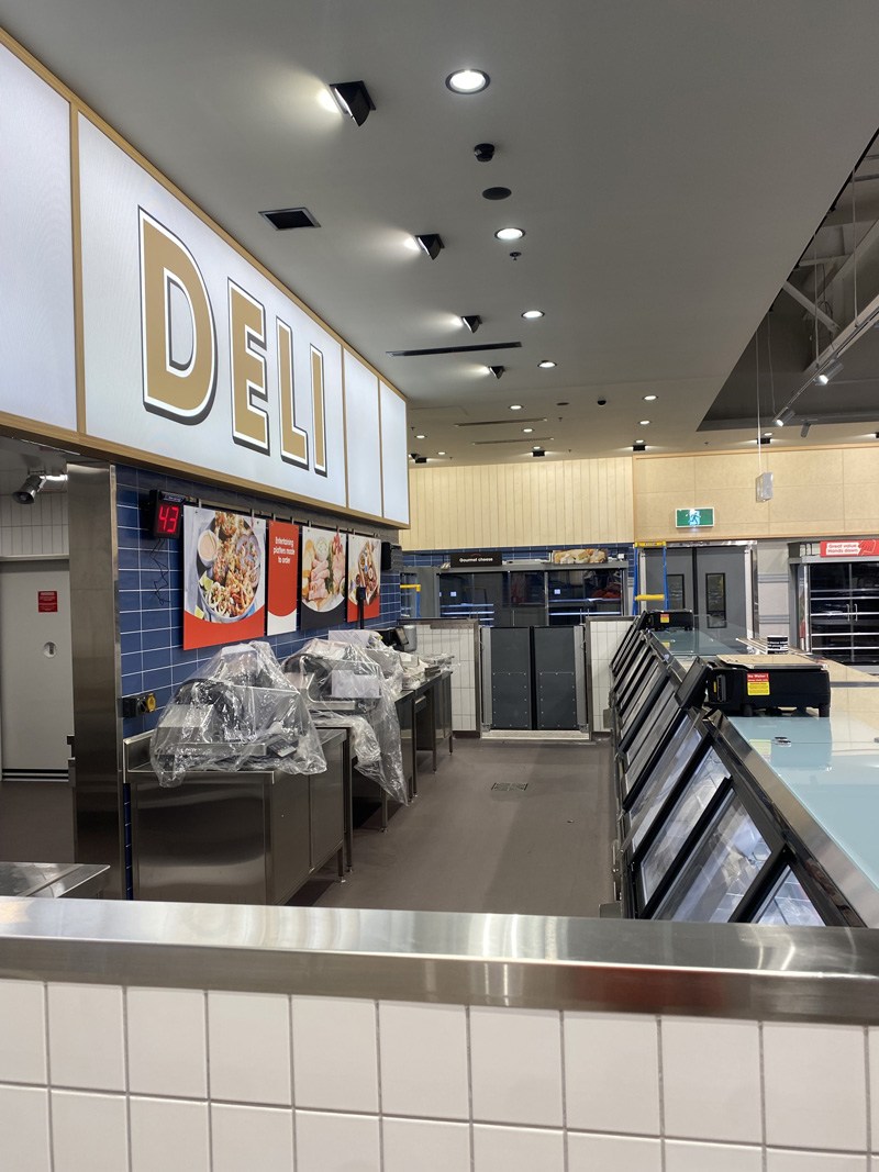 Supermarket deli with blue wall tiles and a white tiled counter base