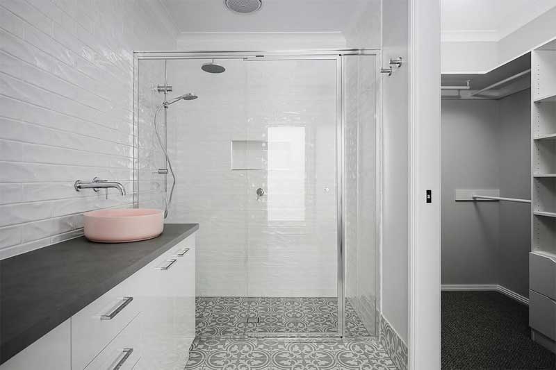 Bathroom with a glass shower, patterned floor tiles and pink vessel basin