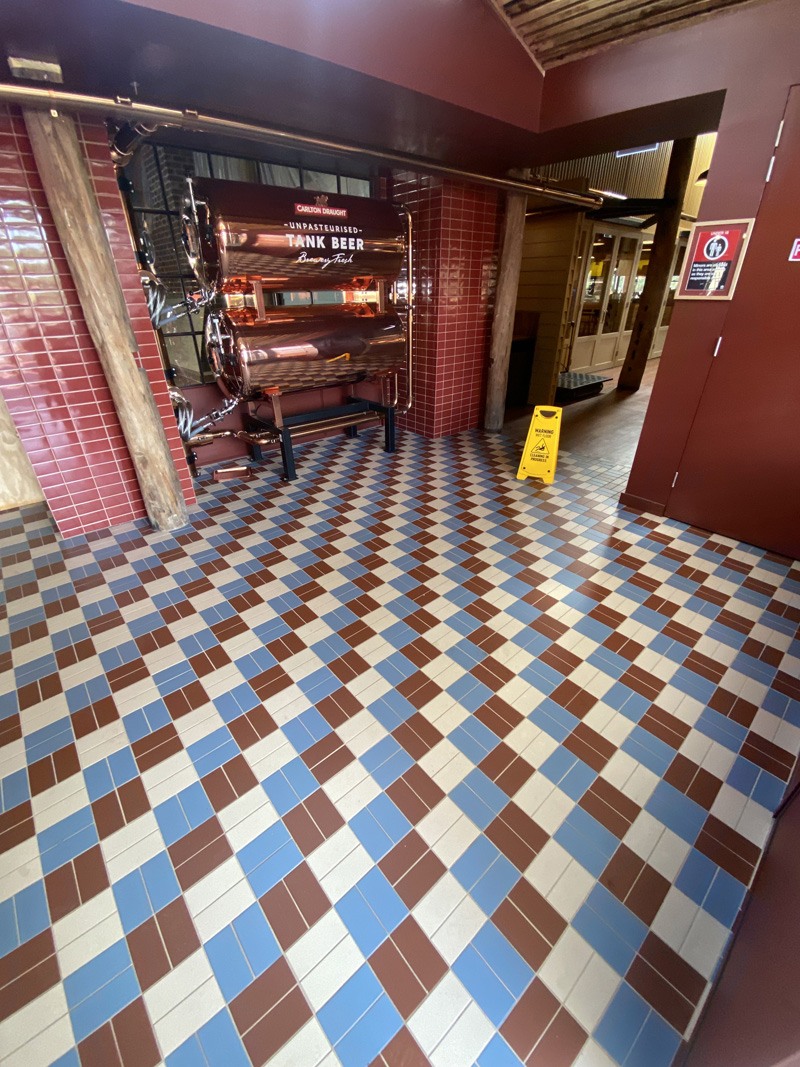 Red, blue and cream diamond-pattern floor tiles beside a Tank Beer display