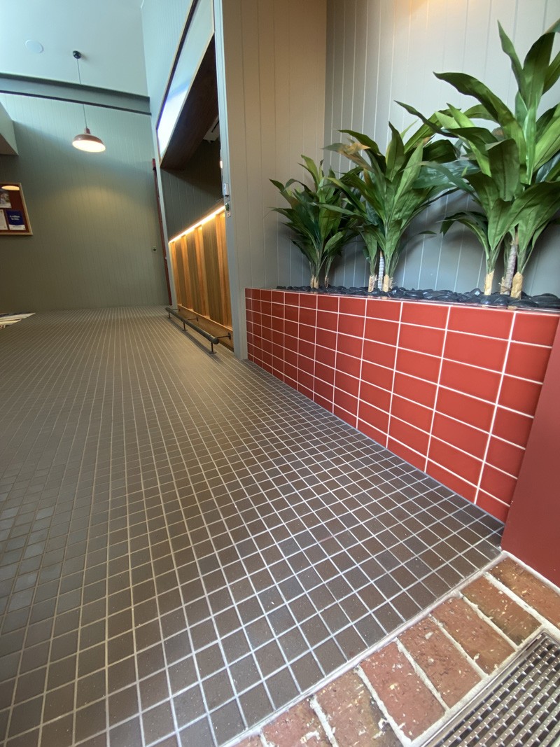 Small brown floor tiles beside a red tiled planter box