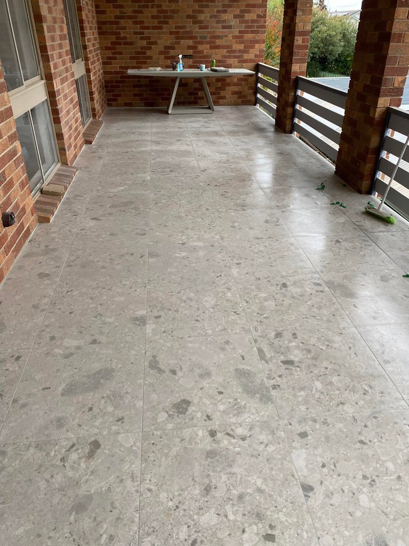 Large terrazzo-look floor tiles on a covered brick verandah