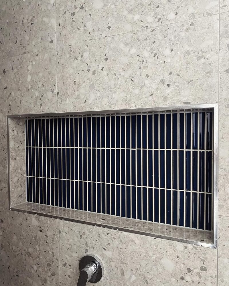Navy finger tile niche set in terrazzo-look wall tiles, front view
