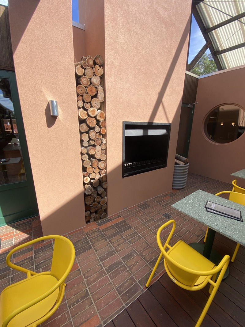 Brick-look floor tiles in a courtyard with yellow chairs and an outdoor fireplace
