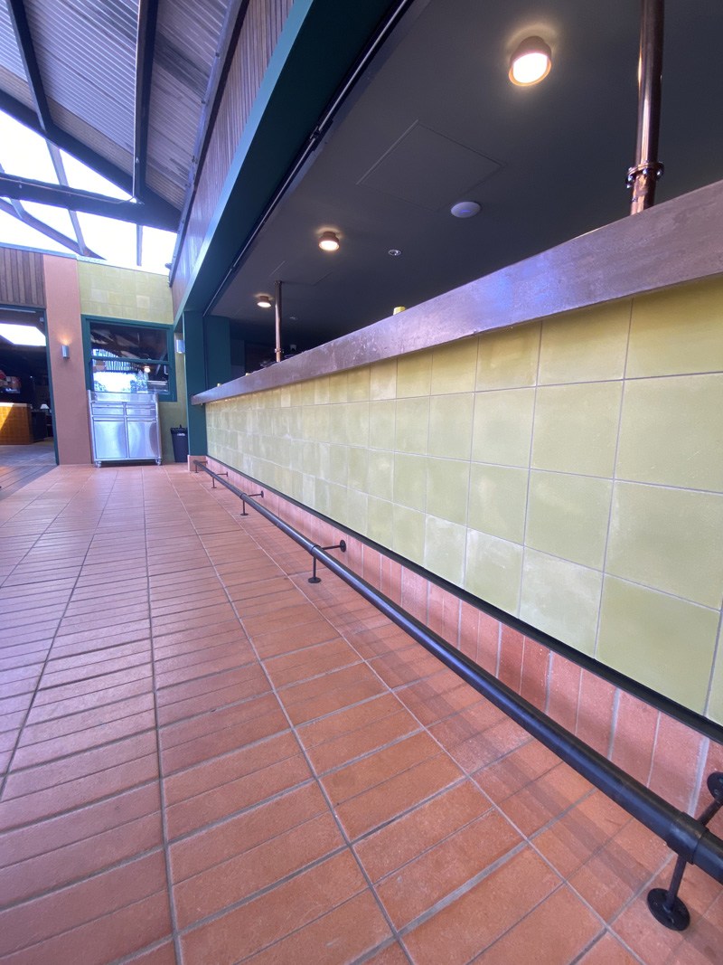 Terracotta floor tiles and pale green wall tiles along a long bar