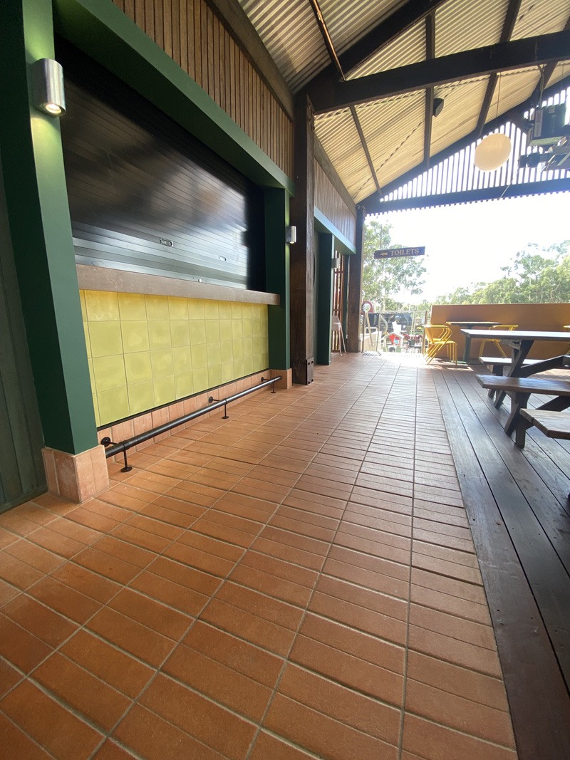Terracotta floor tiles and yellow wall tiles along a covered outdoor bar