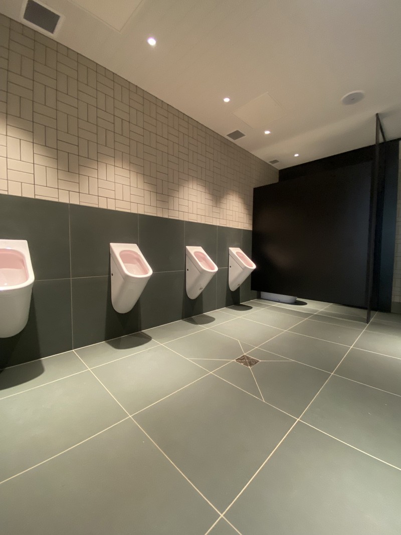 Men's toilets with large grey floor tiles and dark wall tiles