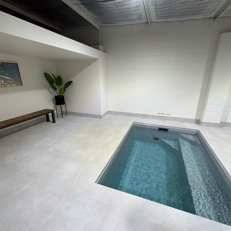 Pale floor tiles around a plunge pool beside a timber bench