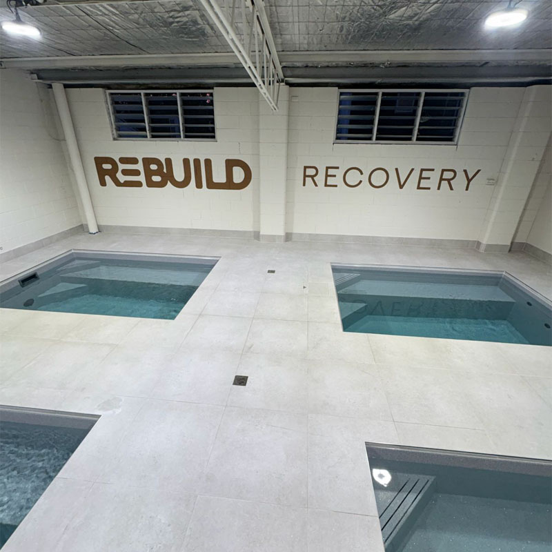 Pale floor tiles around four plunge pools under a Rebuild Recovery sign