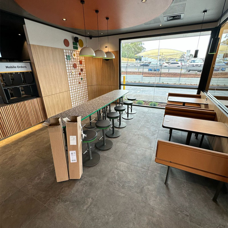 Grey floor tiles in a restaurant dining area with a window bench and stools
